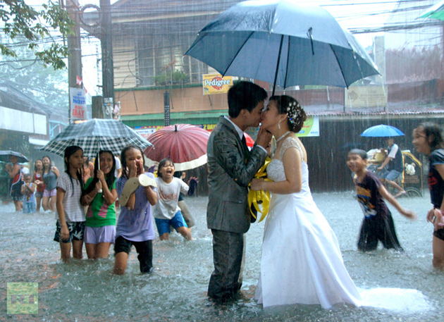 Ramoncito Campo kisses his wife Hernelie Ruazol Campo on a flooded street during a southwest monsoon that battered Manila (Courtesy: Ramoncito Campo).