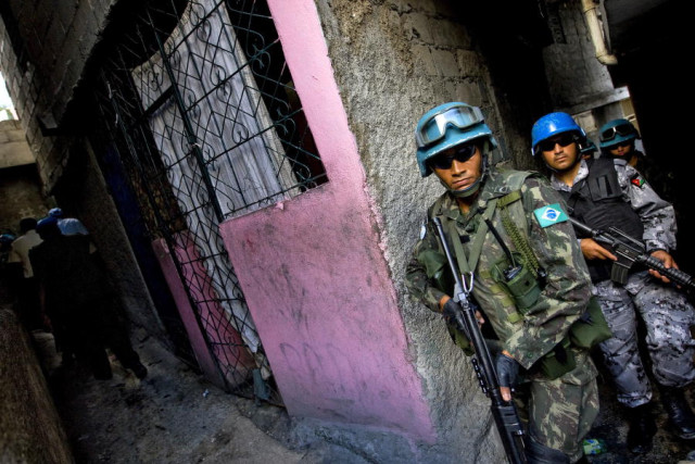Members of the Brazilian contingent of the United Nations Stabilization Mission in Haiti (MINUSTAH) walk through an alley during a patrol of the streets of the city as part of a coordinated security programme of the military, the United Nations and the national police force during the holiday season. 18/Dec/2008. UN Photo/Marco Dormino. www.unmultimedia.org/photo/