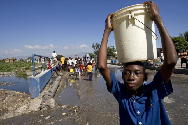 A boy in Cité Soleil carries away a hard-won bucket of water from a broken water pipe where many Haitians struggled for their share. The shanty town of Cité Soleil has been left with severely diminished water resources after a powerful earthquake rocked the area on 12 January. 15/Jan/2010. Cité Soleil, Haiti. UN Photo/Logan Abassi. www.un.org/av/photo/