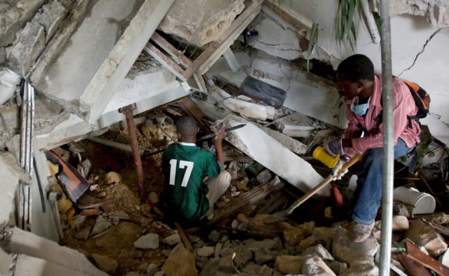 Two Haitians use crowbars, shovels and their hands to clear rubble in an attempt to reach survivors at the Montana hotel that collapsed after an earthquake measuring 7 plus on the Richter scale rocked Port au Prince Haiti just before 5 pm yesterday, January 12, 2009.